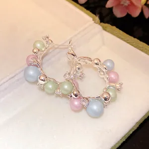 Close-up detail of silver hoop earrings featuring colorful pastel pearls and clear zircons.