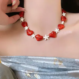 Detail view of a red heart and white star beaded necklace for beach vacations.