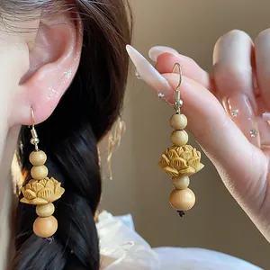 Detail of hand-carved wooden lotus earrings with beads in a vintage Chinese style.