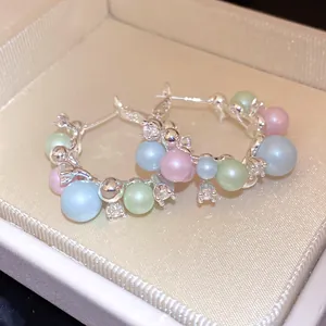 Close-up macro detail of silver hoop earrings featuring pastel pearls and sparkling zircons