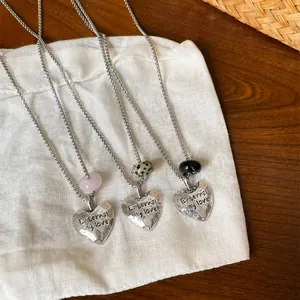 Gros plan de pendentifs cœur en argent froissé avec gravure et perles de pierre naturelle