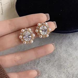 Macro detail of French vintage earrings with pearls and oval zircons in gold setting.