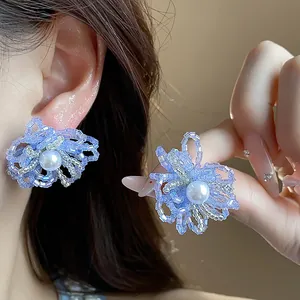 Primer plano de elegantes pendientes de flores con cuentas moradas y una perla central brillante
