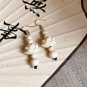 Detailed close-up of Chinese style wooden bead earrings with delicate carved lotus