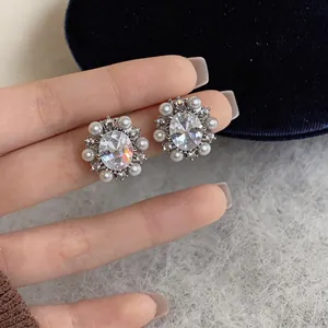 Close-up of vintage French style earrings with zircon and pearls held by hand against velvet