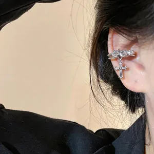 Detailed shot of a vintage 14k gold-plated ear cuff with zircon and cross pendant.