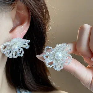 Vista detallada de pendientes de flores de cristal hechos a mano con una perla blanca
