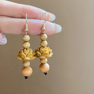 Close-up view of vintage Chinese style hand-carved wooden lotus drop earrings with beads.