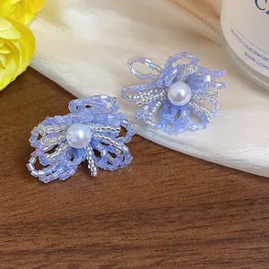 Primer plano de pendientes de flores con cuentas azules y detalle de perla blanca