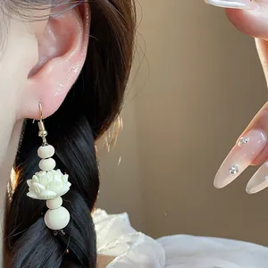 Close-up of vintage Chinese style earring with carved white lotus and wooden beads.