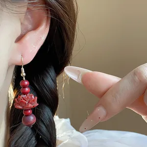 Close-up detail of Chinese style earring with red wooden beads and carved lotus