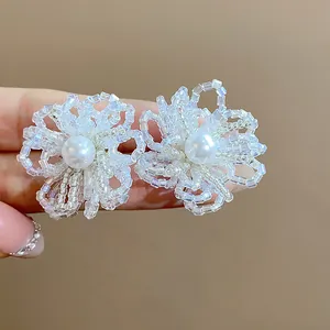 Primer plano detallado de pendientes de flores de cuentas de vidrio con perla elegante