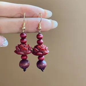 Detailed view of Chinese style wooden bead earrings with carved red lotus charms