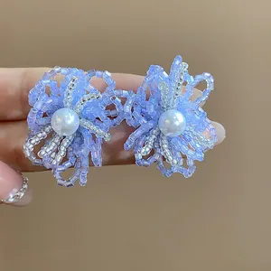 Primer plano de pendientes de flores con cuentas azules y una perla blanca central