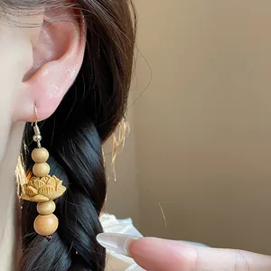 Close-up detail of Chinese style wooden bead earrings with carved lotus design