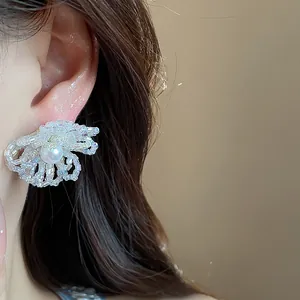 Pendientes de flores de cristal con detalle de perlas en la oreja de una modelo