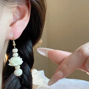 Close-up macro detail of traditional Chinese style carved wooden lotus drop hook earrings