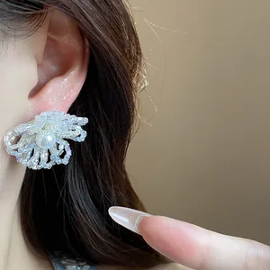 Primer plano detallado de pendientes de flores de cristal con perla en una modelo