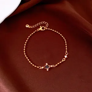 Close-up of elegant gold bead chain bracelet with star zircon detail on brown satin.
