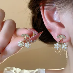 Dettaglio di eleganti orecchini a forma di ciliegia con perle e zirconi luccicanti