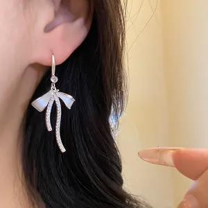 Elegant French style white enamel bow drop earrings with sparkling zircons worn by model