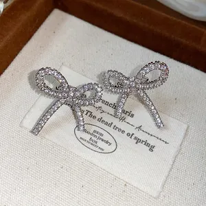 Close-up view of sparkling cubic zirconia bow earrings on a vintage fabric jewelry tag