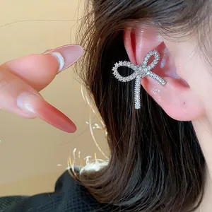Detailed macro view of a sparkling zircon bow-shaped ear cuff worn on the ear bone.