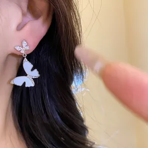 Close-up of elegant French-style butterfly earrings with zircons and white oil drip.