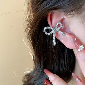 Close-up view of a sparkling silver zircon bow ear cuff worn on an elegant female ear.