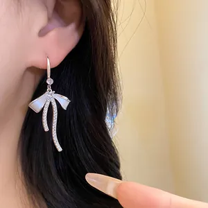 Close-up detail of a elegant French style zircon bow earring with white enamel finish