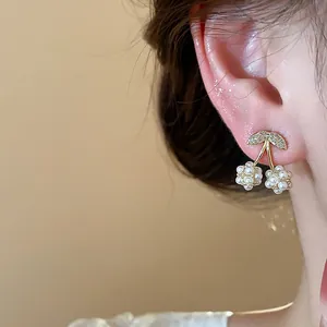 Primo piano di eleganti orecchini a lobo ciliegia con perle e zirconi sul modello
