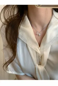 Vue détaillée d'un collier de perles mauves avec pendentif raisin porté par un mannequin