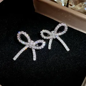Close-up of sparkling zircon bow-shaped ear clips on a black velvet background