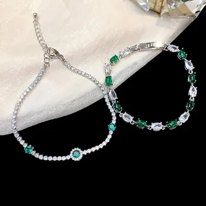 Close-up view of sparkling green zircon tennis and oval stone bracelets on a black background