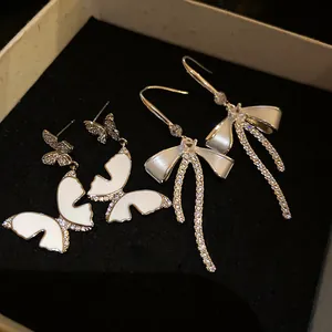 Detailed macro shot of elegant white enamel butterfly and sparkling zircon bow earrings