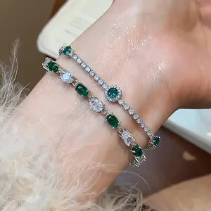 Close-up of elegant silver bracelets with sparkling green and white oval zircons.