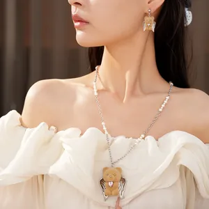 Dettaglio di una collana a forma di orsetto floccato con perle, zirconi e ali d'angelo