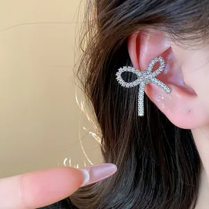 Close-up macro view of a sparkling zircon bow ear cuff elegantly worn on a woman's ear