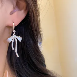 Close-up view of French style bow earring with sparkling zircons and white enamel