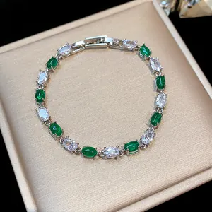 Close-up of green and white oval zircons on a silver-tone geometric bracelet.