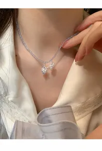 Vue rapprochée détaillée d'un collier en perles avec pendentifs raisin en strass et perle.