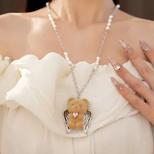 Dettaglio di un ciondolo a forma di orsetto floccato con ali su una collana di perle