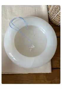 Vue rapprochée d'un collier de perles bleues avec pendentifs raisin et fleur de perle dans un bol.
