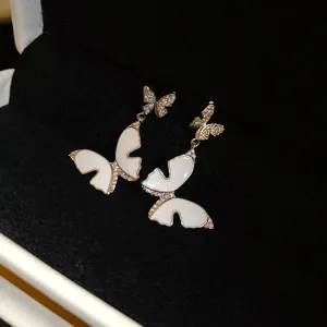 Close-up view of elegant butterfly drop earrings with white enamel and zirconia