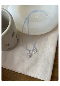 Vue détaillée du collier de perles bleu clair avec pendentif perle et raisin violet