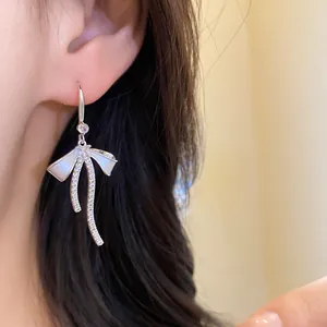 Close-up of elegant French style silver bow earrings with zircon and white enamel.
