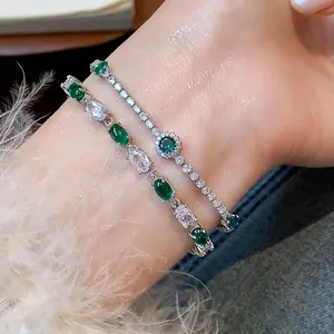 Close-up of elegant silver bracelets with sparkling green and white zircon stones on wrist.