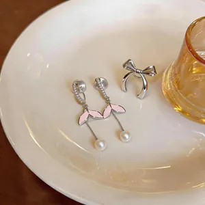 Dettaglio degli orecchini a clip a coda di sirena in smalto rosa con perle e zirconi