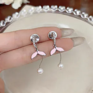 Primo piano di orecchini a clip a coda di sirena rosa con perle e zirconi brillanti.