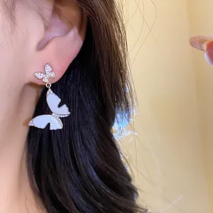 Close-up detail of French style silver butterfly earring with white enamel and zircons